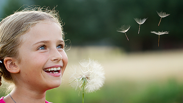 Lachendes Mädchen mit Pusteblume